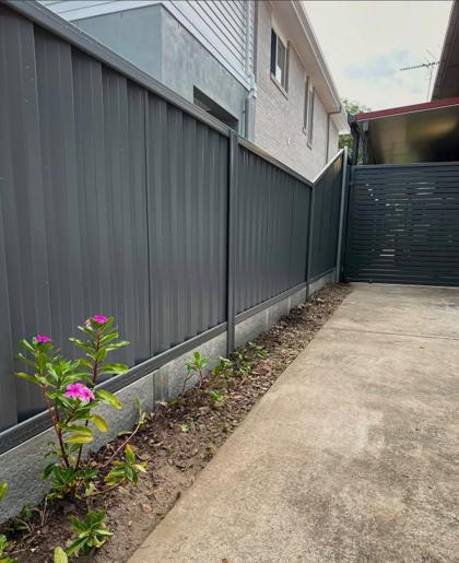 Charcoal Colorbond fence with a matching slat gate along a driveway, by Elite 7 Fencing, Brisbane