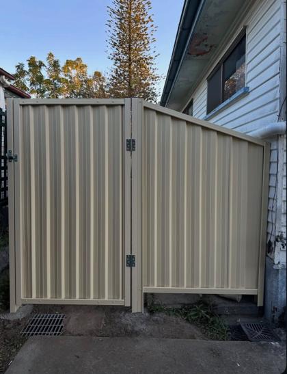 Cream Colorbond side-access gate beside a stepped fence panel by Elite 7 Fencing, Brisbane