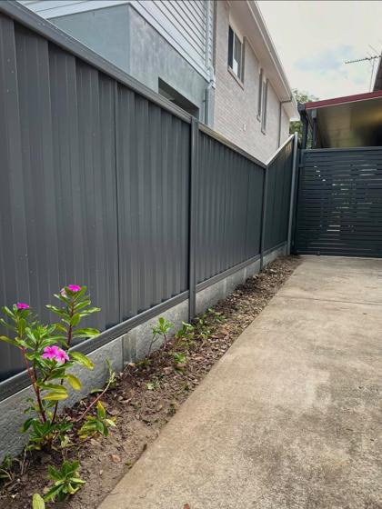 Charcoal Colorbond fence with a matching slat gate along a driveway, by Elite 7 Fencing, Brisbane
