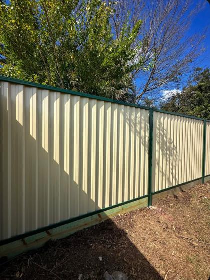 Cream Colorbond boundary fence with green posts and rails by Elite 7 Fencing, Brisbane