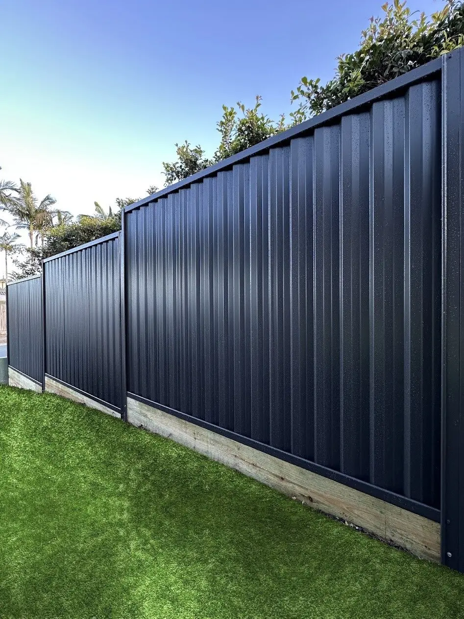Black Colorbond fence stepping down on timber sleepers, built by Elite 7 Fencing
